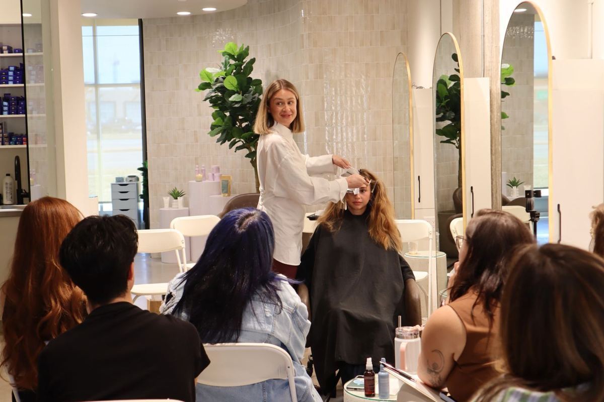 A salon room of stylists watching a demonstration