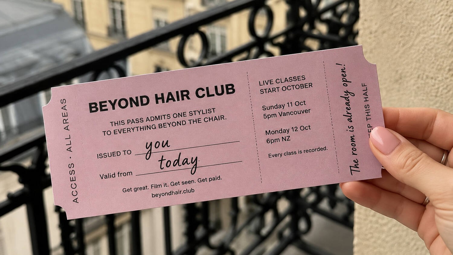 A hand holding a Beyond Hair Club pass on a Paris balcony
