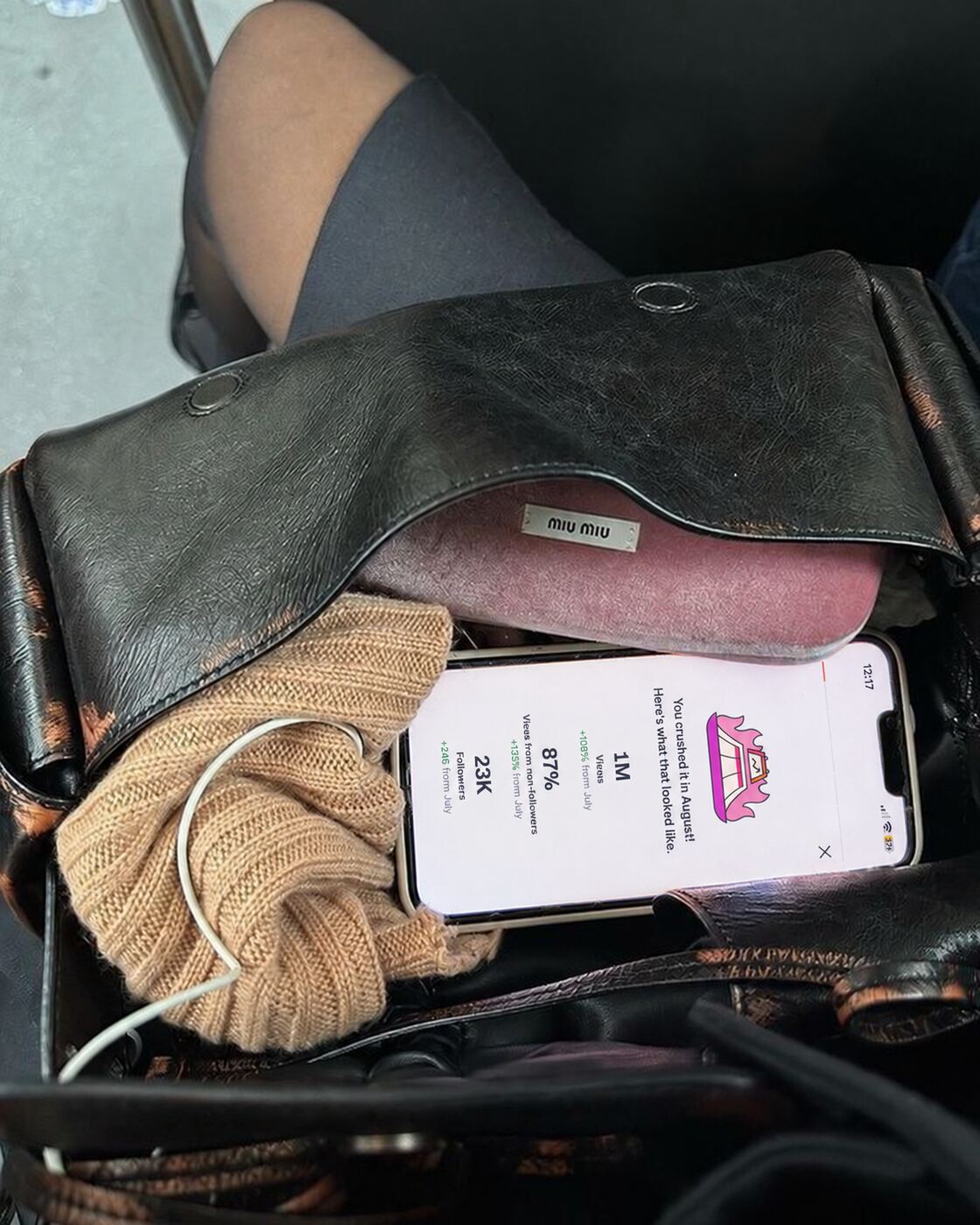 A phone in a bag showing a month recap: one million views and 23 thousand followers